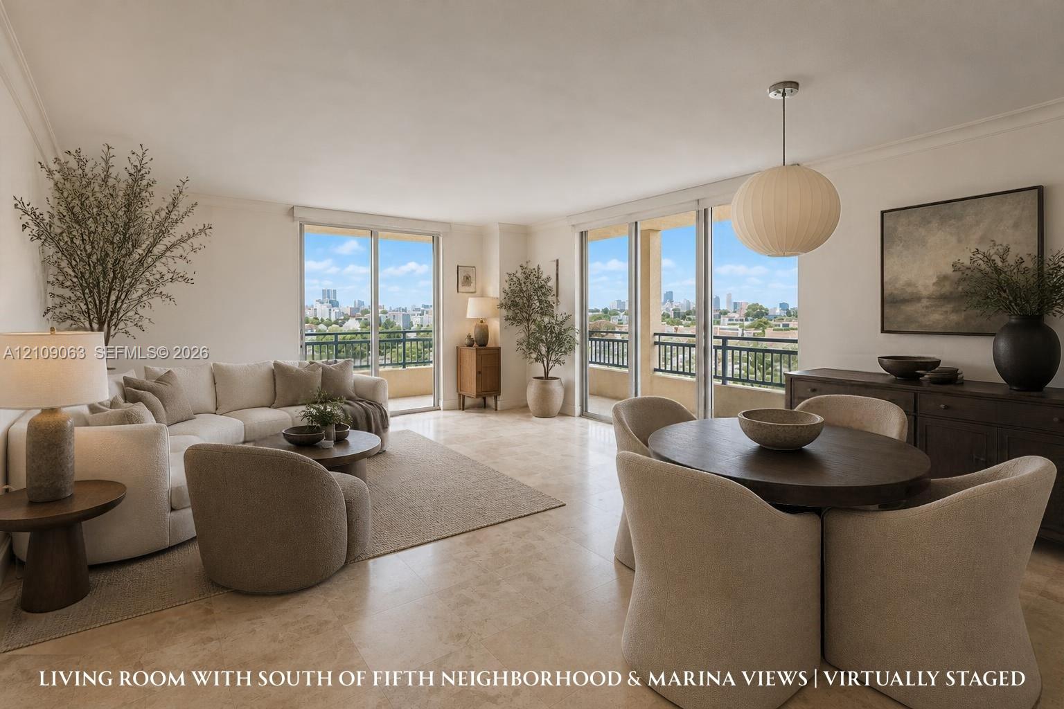 Open-concept interior featuring light-toned stone tile flooring, dual floor-to-ceiling glass sliding doors, a suspended spherical light fixture, and an expansive covered balcony with metal railing