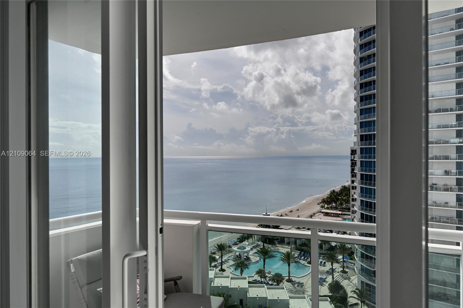 Private covered balcony featuring white railing and floor-to-ceiling glass sliding doors
