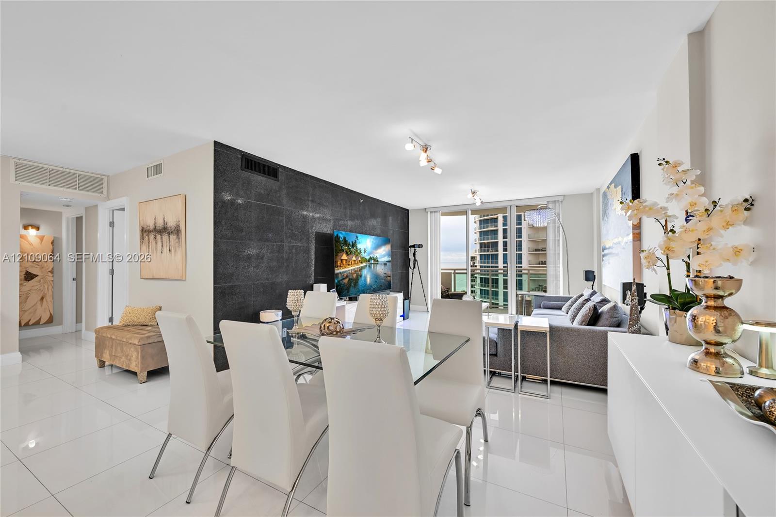 Living area featuring large-format polished tile flooring, a prominent black stone feature wall, sliding glass doors, and adjustable track lighting