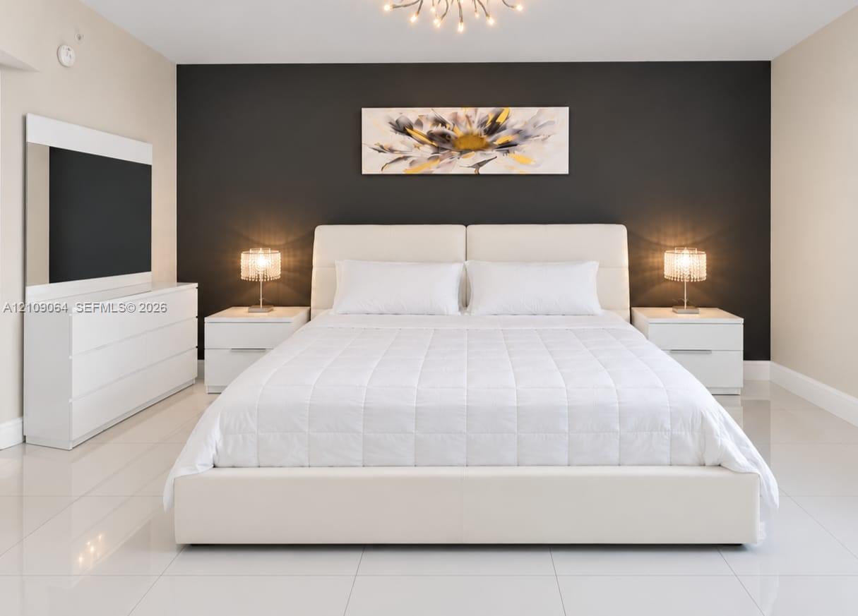Neutral-toned room featuring a dark charcoal accent wall, polished tile flooring, and a contemporary multi-arm chandelier