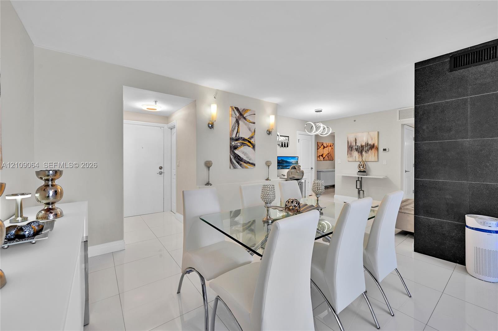 Open-concept interior featuring large-format tile flooring, a prominent black stone feature wall, dual wall-mounted light fixtures, and recessed ceiling lighting