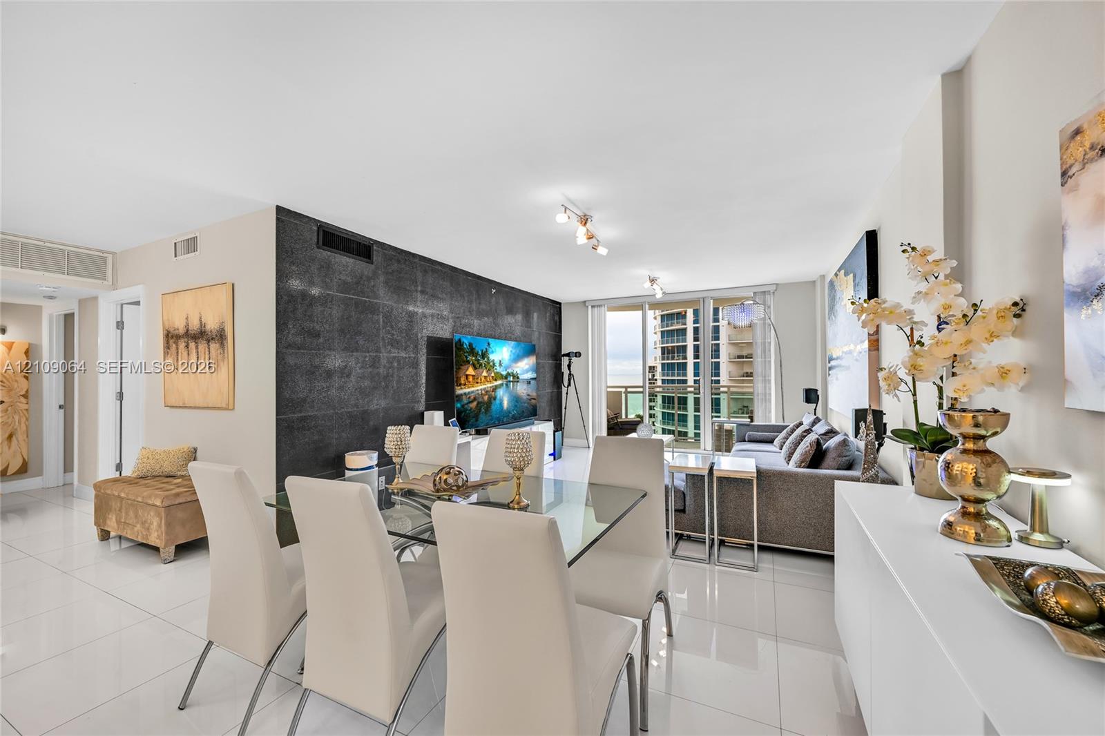 Large-format tile flooring, textured black accent wall, and glass sliding doors providing exterior access