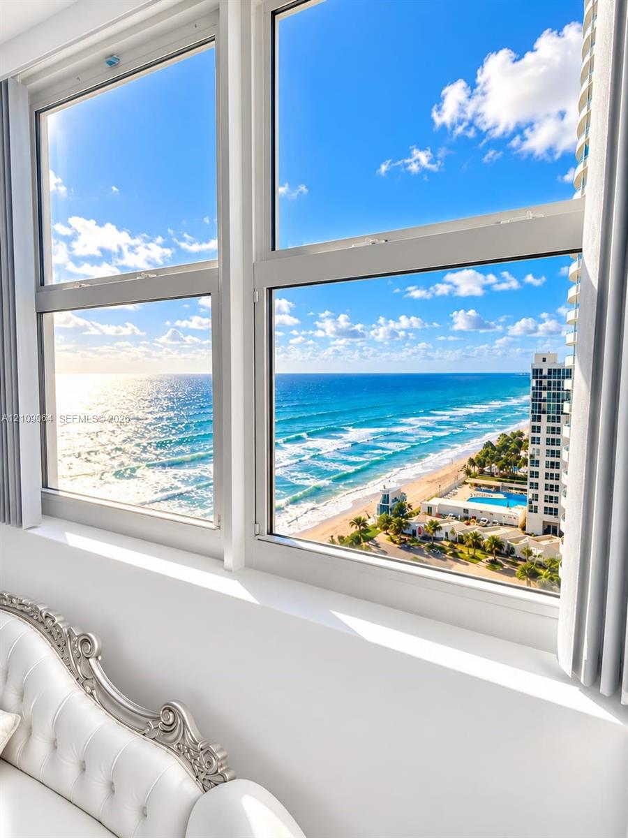 Large-pane windows featuring white frames, showcasing panoramic ocean, shoreline, and coastal scenery