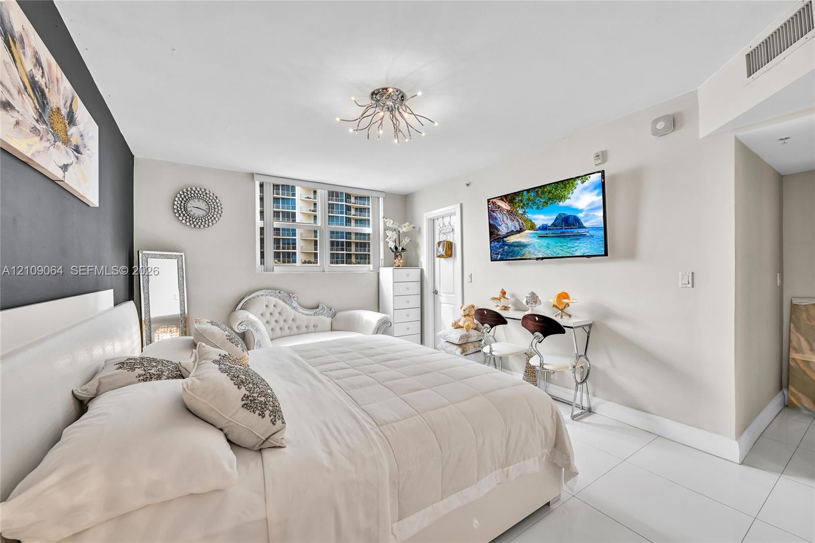 Bright room featuring white tile flooring, a dark charcoal accent wall, and a multi-arm contemporary ceiling light fixture