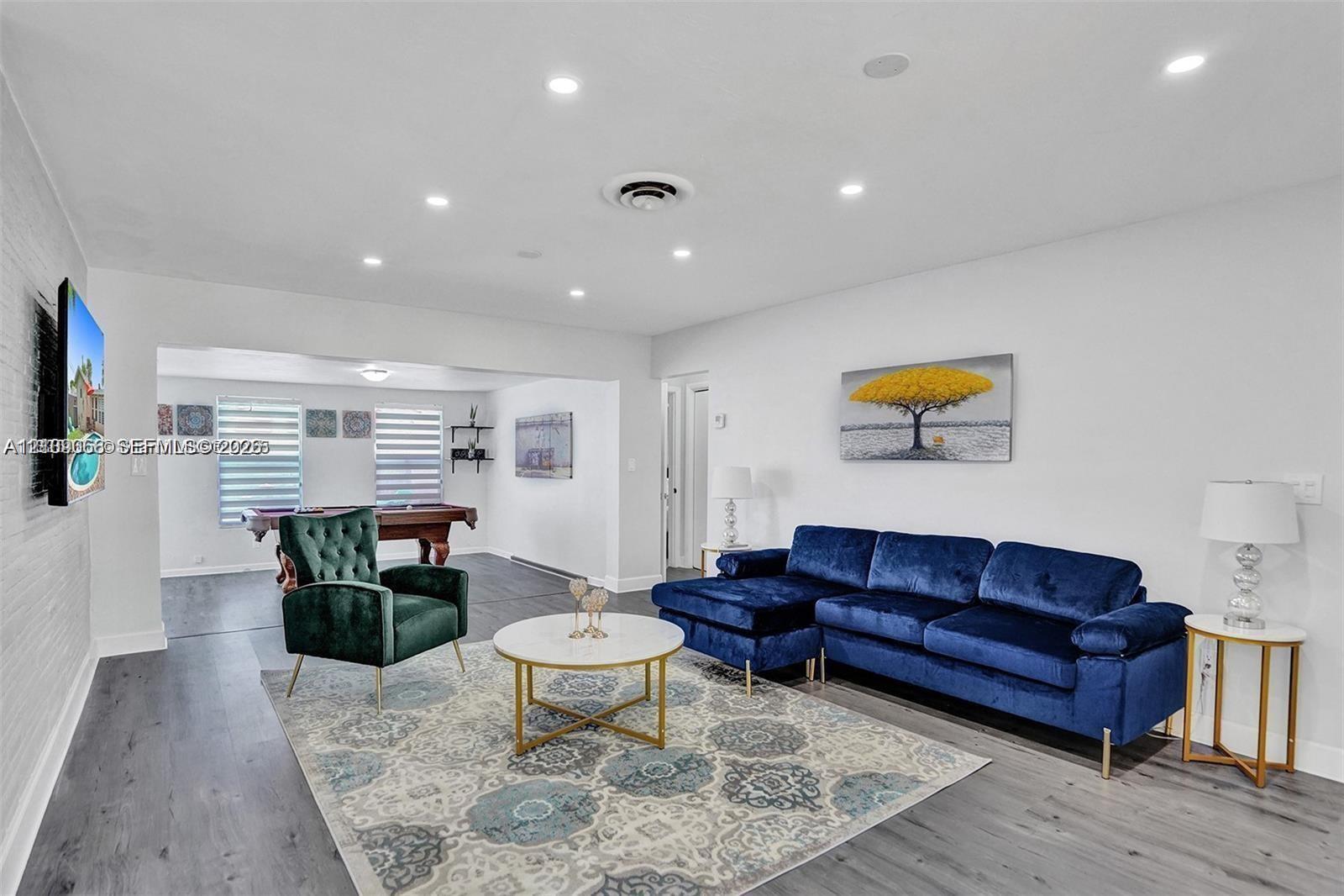 Open-concept interior featuring wood-finish flooring, recessed lighting, and horizontal window blinds