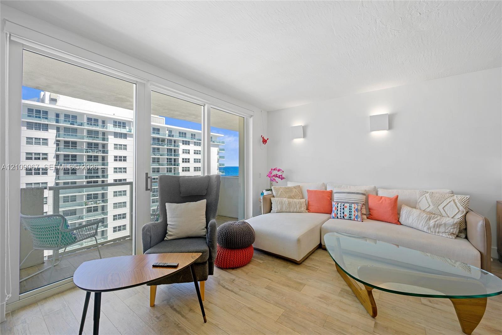 Floor-to-ceiling sliding glass doors, wood-finish flooring, and wall-mounted light fixtures Floor-to-ceiling sliding glass doors, wood-finish flooring, and wall-mounted light fixtures
