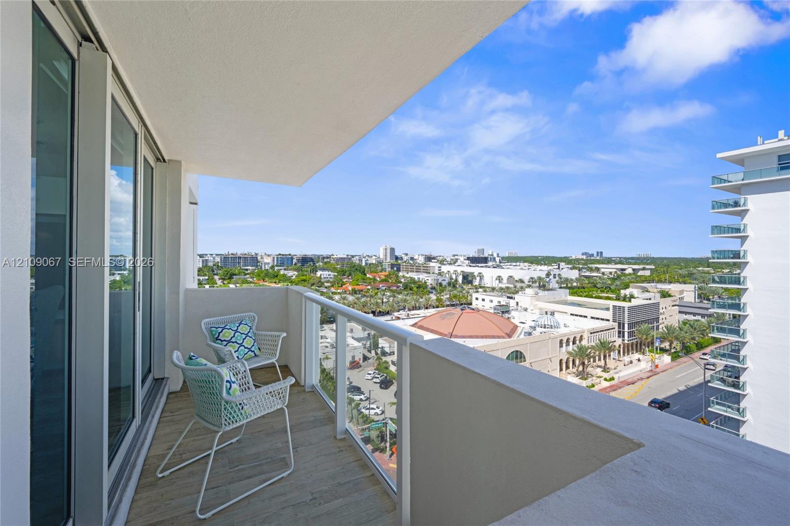 Covered balcony featuring wood-finish flooring and a glass railing with a powder-coated frame