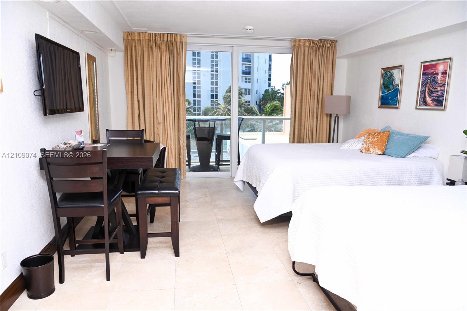 Neutral-toned tile flooring, floor-to-ceiling glass sliding doors, and a private balcony featuring a metal railing