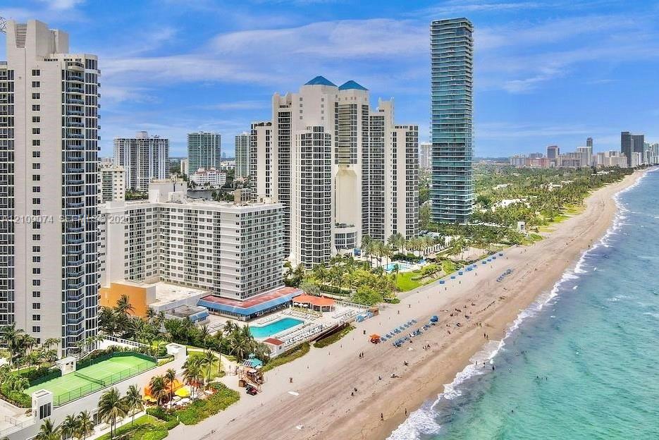 Coastal high-rise buildings featuring expansive ocean frontage, swimming pools, and tennis courts
