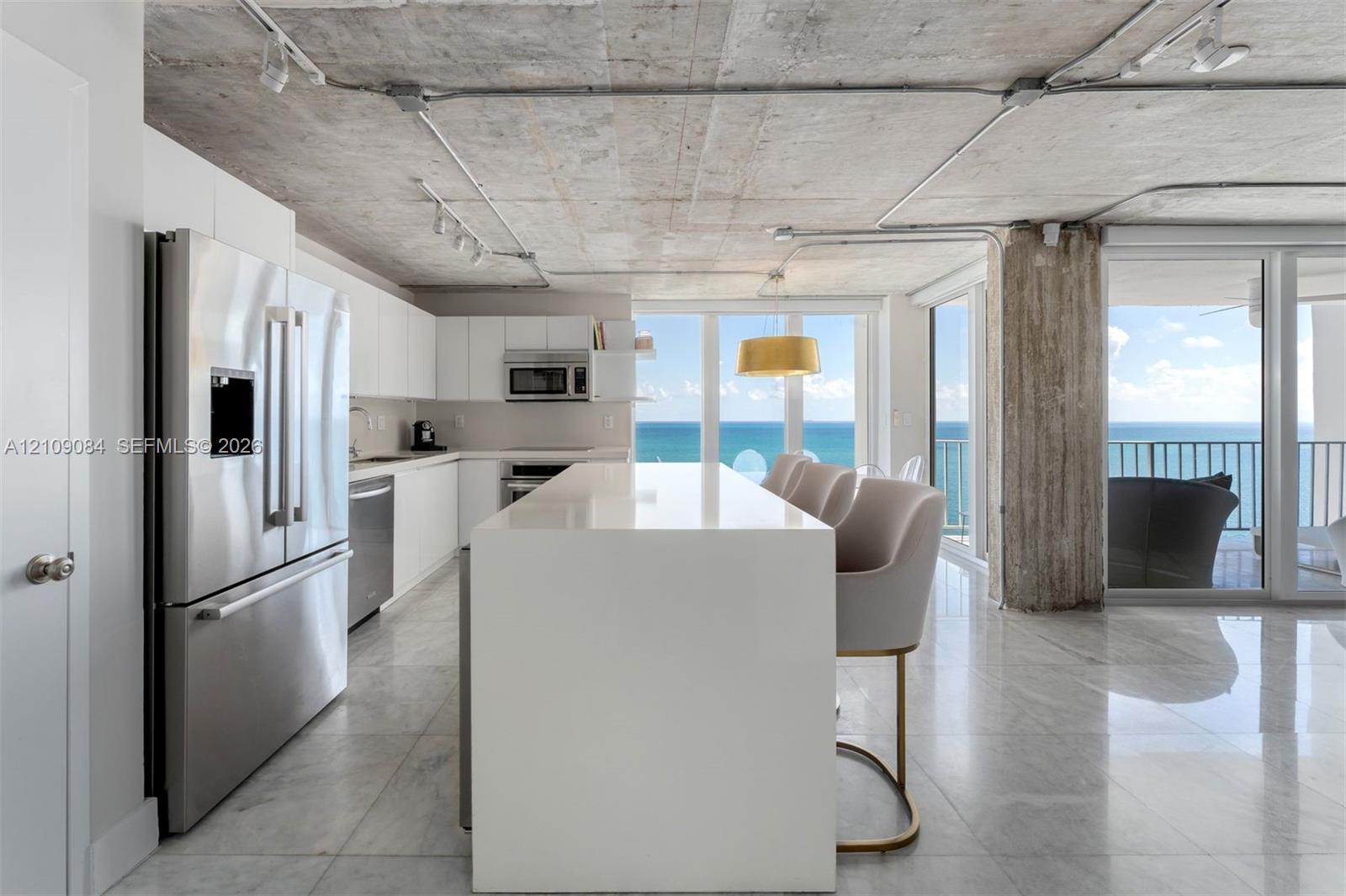 Floor-to-ceiling windows, exposed concrete ceiling, industrial-style drum pendant lighting, polished stone-finish flooring, and exposed concrete structural pillar