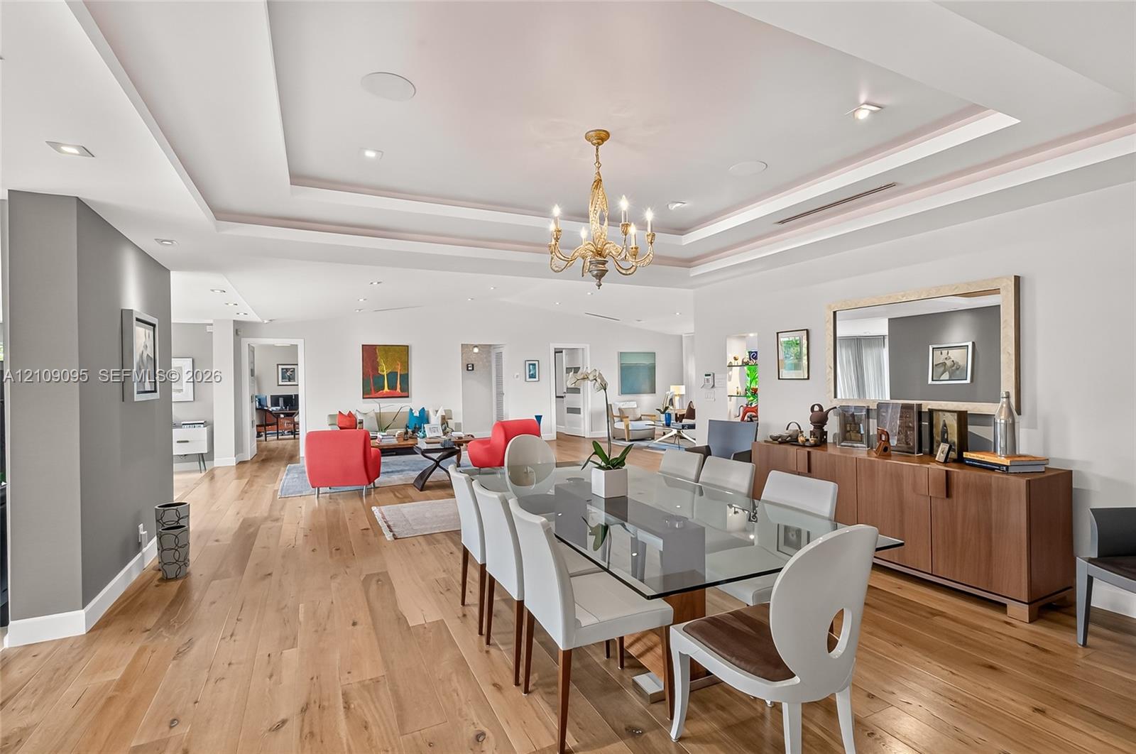 Open floor plan featuring wood-finish flooring, recessed lighting, multi-tiered tray ceiling, and a traditional six-arm chandelier