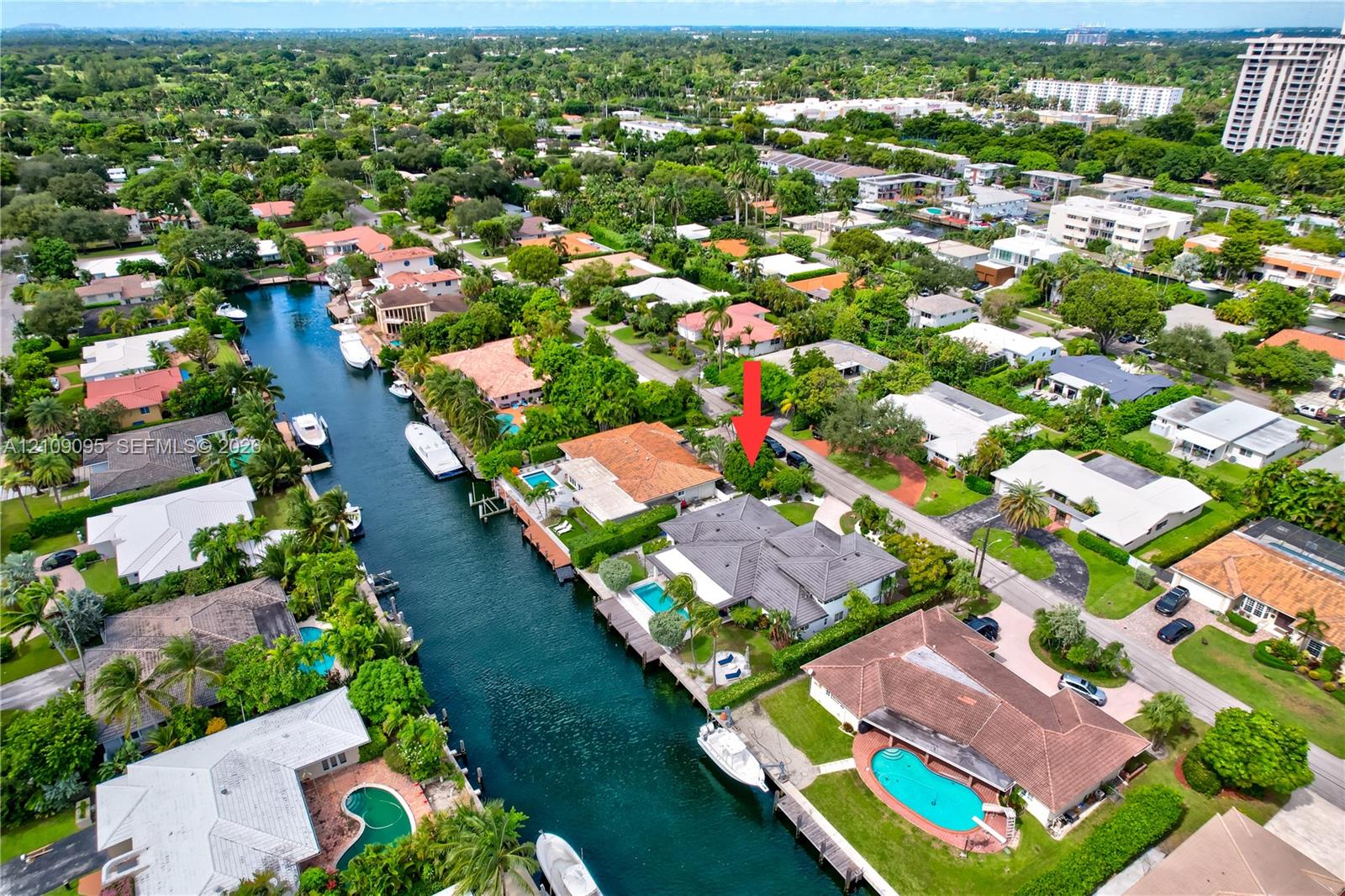 Aerial perspective of a waterfront property featuring direct canal access, a private swimming pool, and mature perimeter landscaping