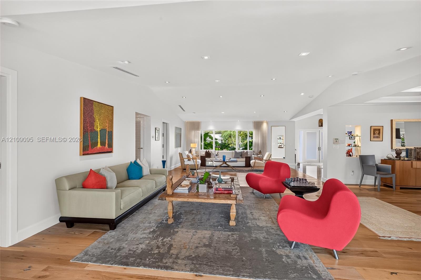 Wide-plank wood-finish flooring, recessed ceiling lighting, and large paneled windows featuring exterior greenery