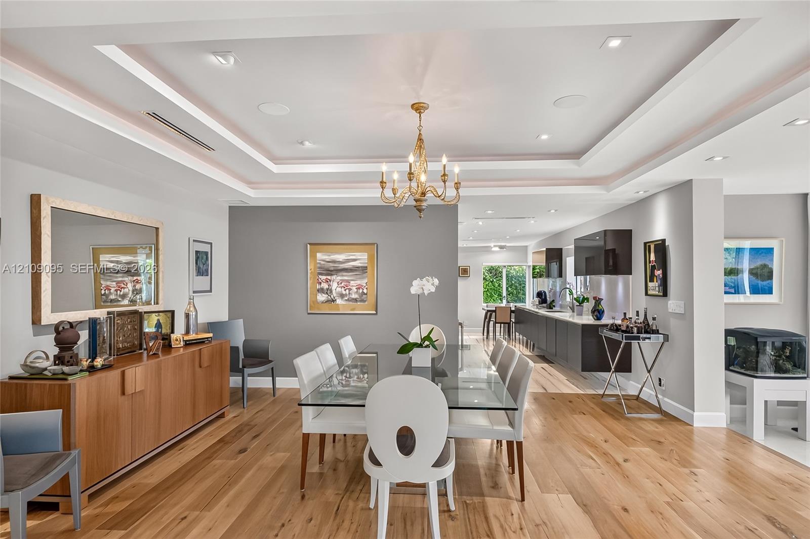 Tray ceiling with recessed lighting, wood-finish flooring, and a central chandelier