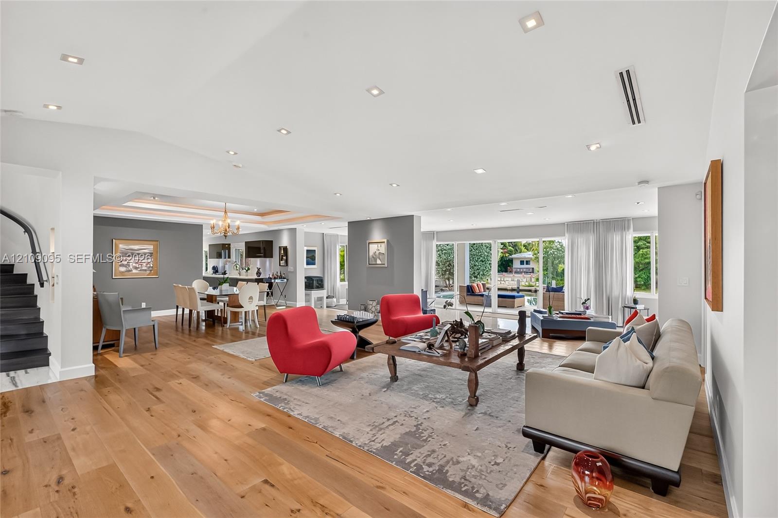 Open-concept interior featuring wood-finish flooring, recessed lighting, expansive glass sliding doors, and a tray ceiling
