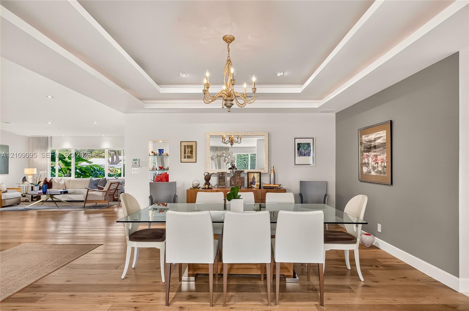 Dining area featuring wood-finish flooring, a double tray ceiling, an ornate metal chandelier, a recessed wall niche, and an accent wall