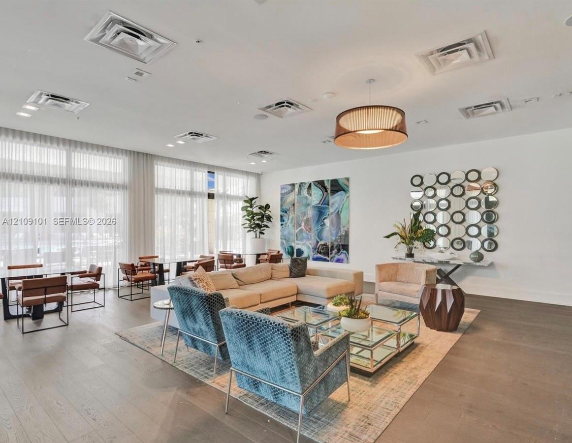 Expansive interior featuring floor-to-ceiling windows, wood-finish flooring, recessed ceiling lighting, and a circular drum pendant light fixture