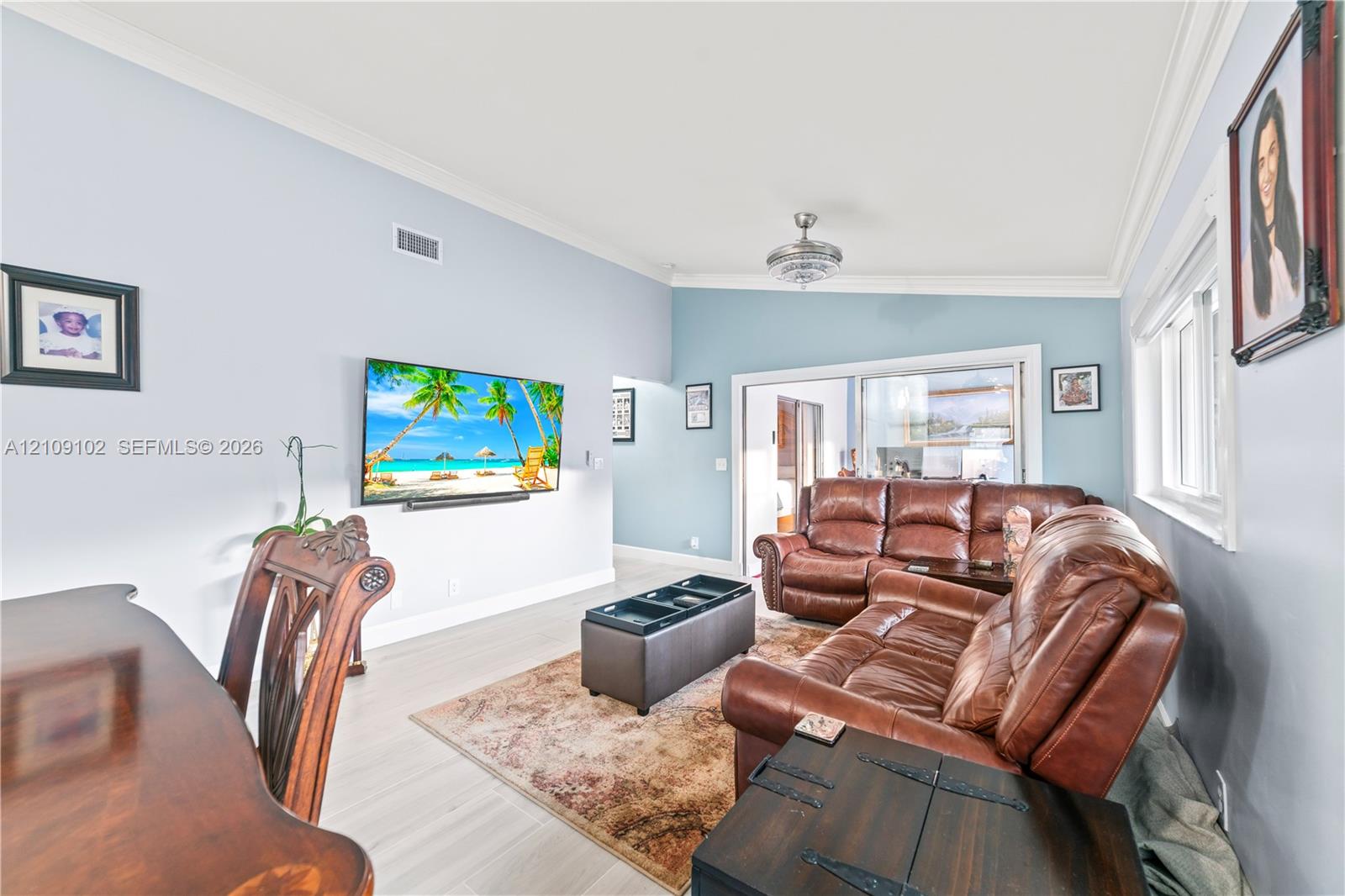 Vaulted ceilings featuring a polished nickel ceiling fan, wood-finish flooring, and crown molding