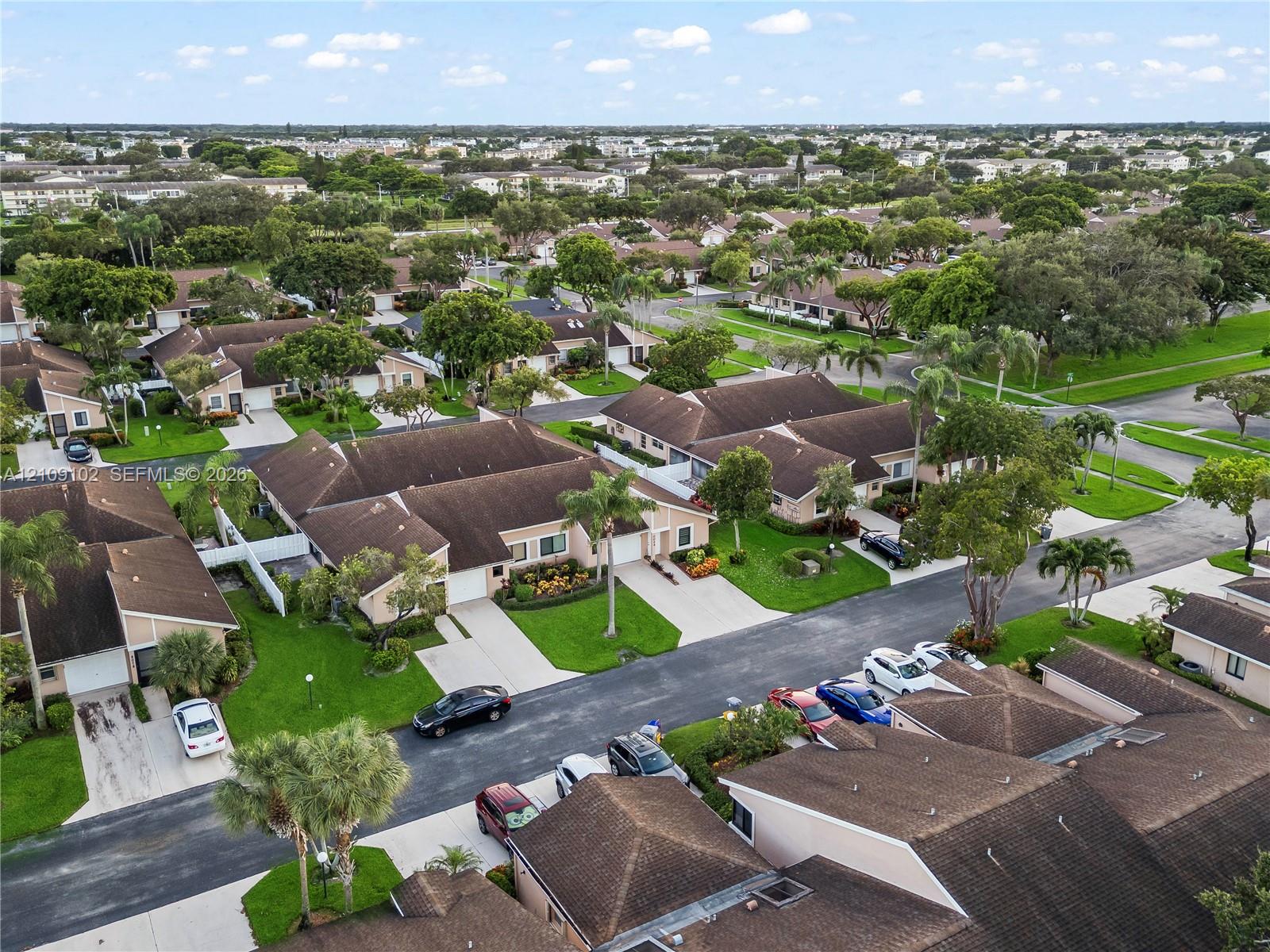 Aerial perspective of a residential community featuring single-story structures with tiled roofs, private driveways, and established tropical landscaping