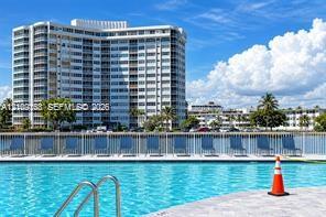 Swimming pool with metal handrail, concrete pool deck, and perimeter fencing