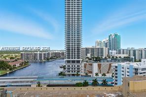 High-rise tower featuring a glass facade, situated along a waterfront canal