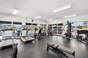 Fitness facility featuring extensive floor-to-ceiling windows, recessed rectangular lighting, and durable rubberized flooring