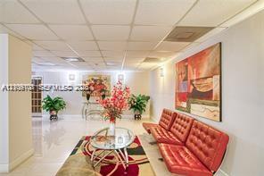 Open-plan interior featuring polished stone flooring, drop-tile ceiling, and wall-mounted light fixtures