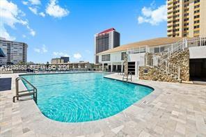 Outdoor swimming pool featuring a paved stone deck, stone exterior wall accents, and metal stair railing