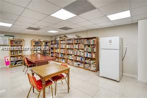 Built-in floor-to-ceiling wooden shelving, drop ceiling with recessed lighting, and tile flooring