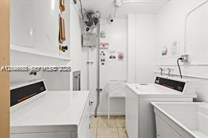 Utility room featuring side-by-side laundry appliances, a built-in utility sink, and stone-finish flooring