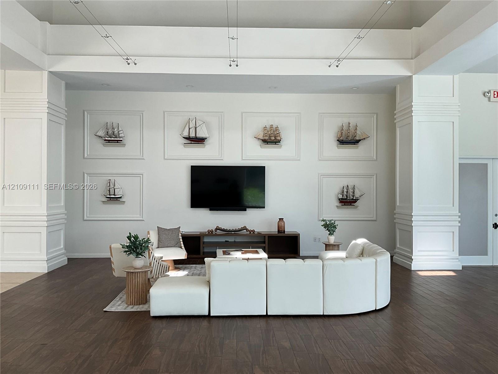 Tray ceiling with recessed lighting, prominent architectural columns with millwork, and dark wood-finish flooring Tray ceiling with recessed lighting, prominent architectural columns with millwork, and dark wood-finish flooring
