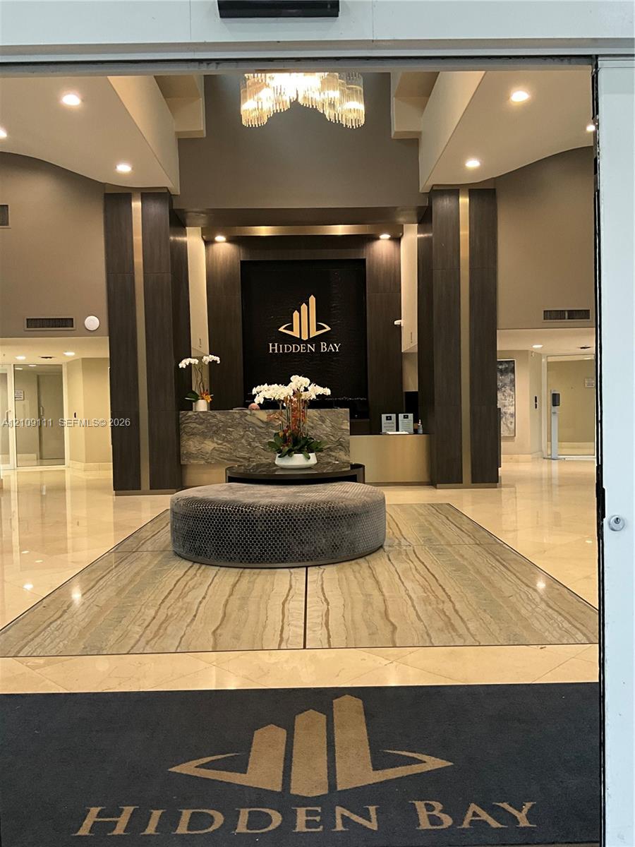 Lobby featuring polished stone flooring, recessed lighting, a stone-front reception desk, and decorative pendant lighting Lobby featuring polished stone flooring, recessed lighting, a stone-front reception desk, and decorative pendant lighting