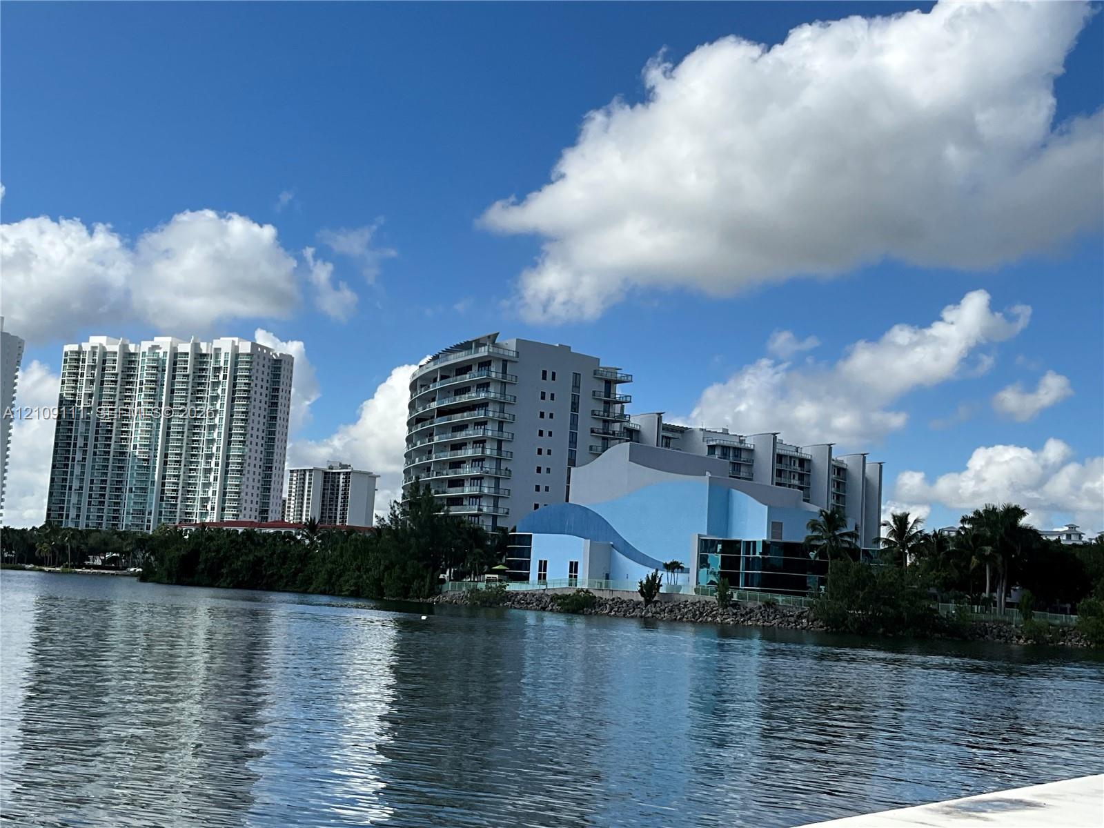 Waterfront location featuring a concrete bulkhead, high-rise architectural structures, and lush tropical vegetation