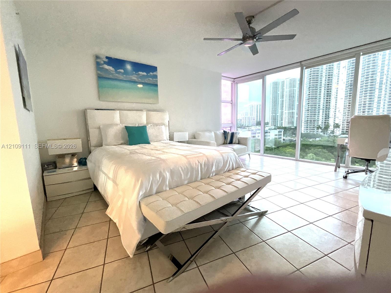 Floor-to-ceiling glass windows, ceramic tile flooring, and a ceiling-mounted light fixture with fan