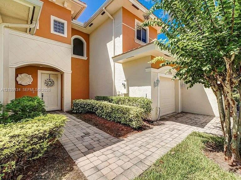 Stucco exterior featuring dual-tone facade, arched entryway, multi-paned windows, paver walkway, and attached one-car garage Stucco exterior featuring dual-tone facade, arched entryway, multi-paned windows, paver walkway, and attached one-car garage