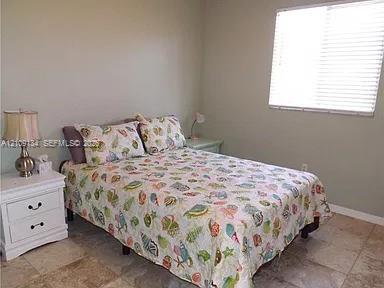 Neutral-toned wall finish, horizontal slat window blinds, and light-toned tile flooring