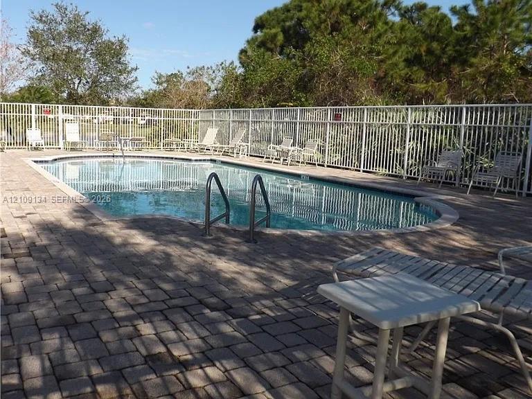 Swimming pool featuring brick paver decking and perimeter aluminum fencing