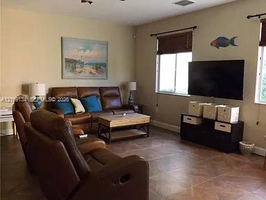 Living area featuring large-format ceramic tile flooring, neutral wall paint, and multiple windows with installed hardware
