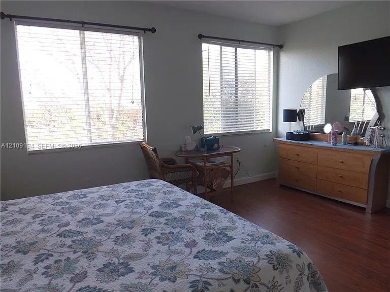 Room featuring wood-finish flooring and two large windows with horizontal blinds