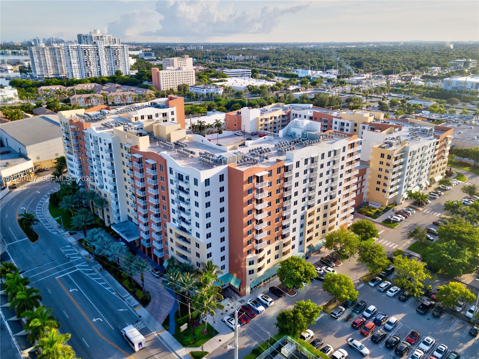 Multi-story mid-rise structure featuring a stucco exterior, private balconies, and a dedicated surface parking area