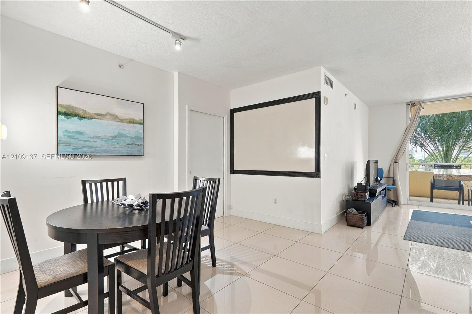 Neutral-toned tile flooring, track lighting, and a private balcony featuring an exterior railing