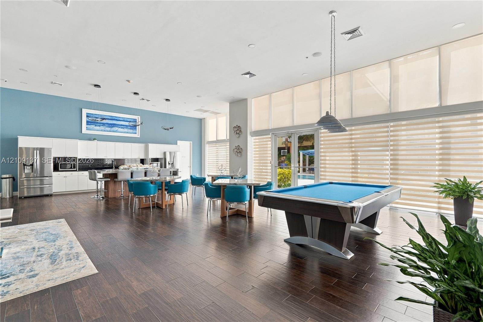 Open-concept room featuring wood-finish flooring, floor-to-ceiling windows, built-in cabinetry, recessed lighting, and suspended multi-light fixtures