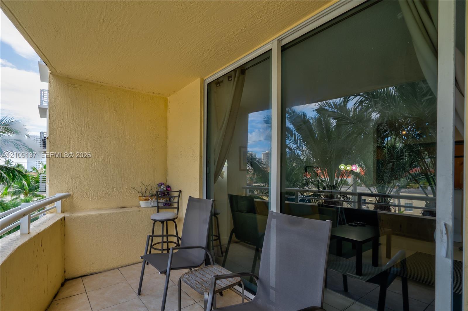 Private balcony featuring tiled flooring, textured wall surfaces, and a metal railing