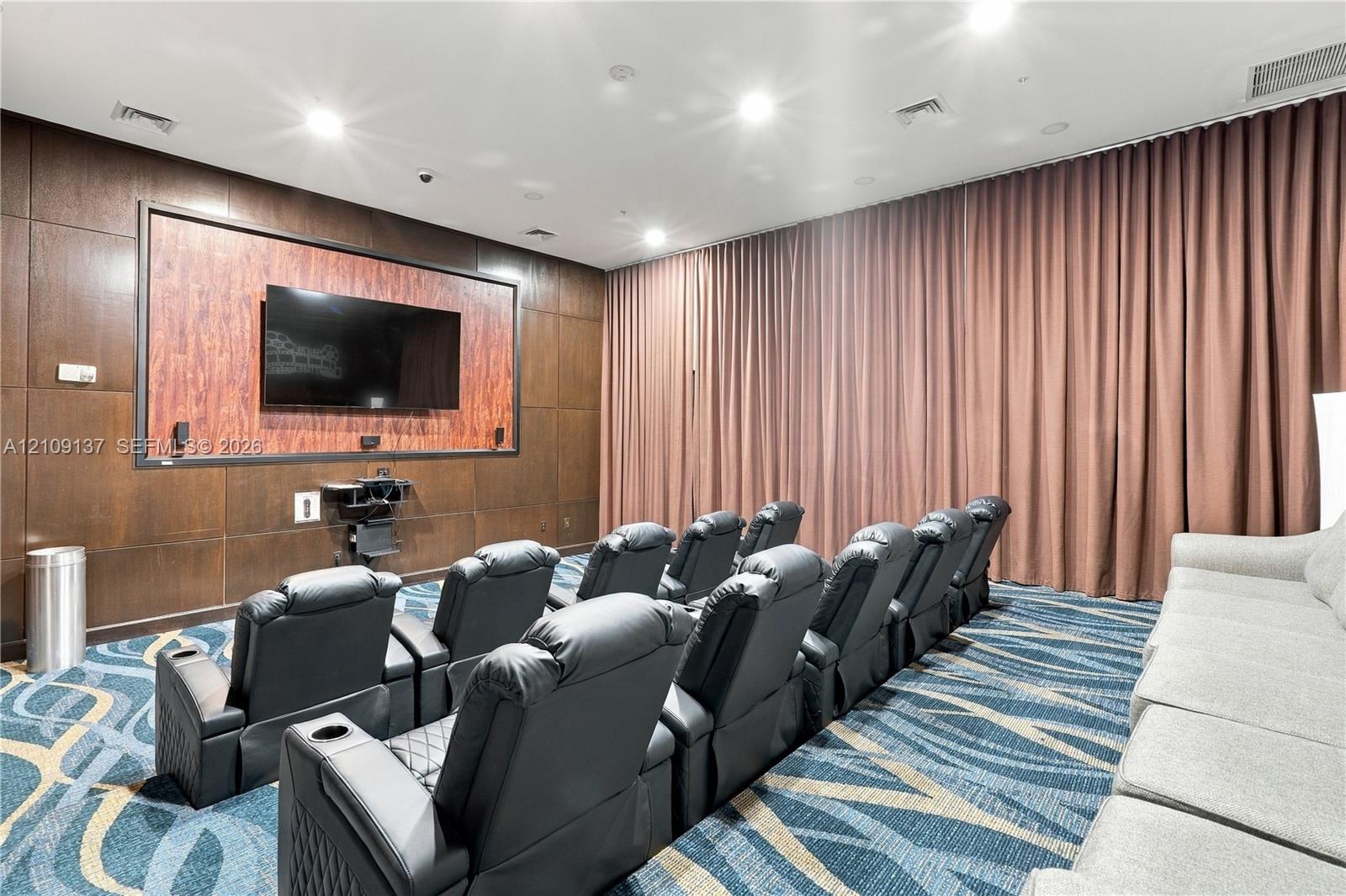 Media room featuring wood-paneled walls, full-height wall drapery, and integrated recessed lighting