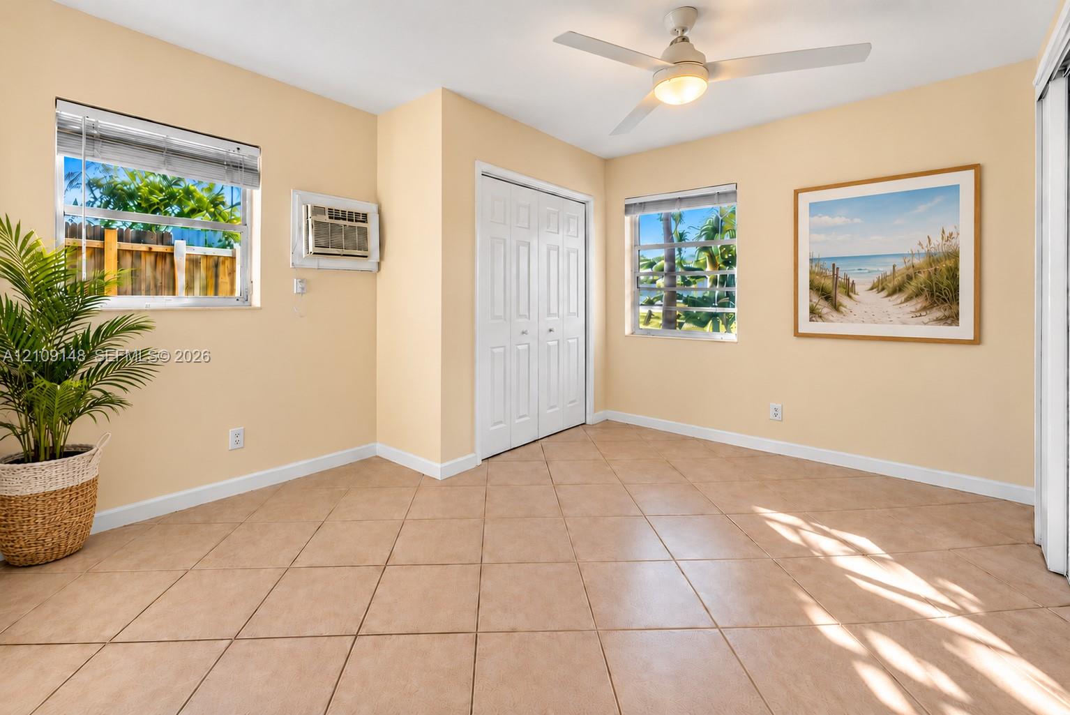 Interior space featuring tile flooring, dual-pane windows, a white ceiling fan with integrated lighting, and a closet with bifold doors