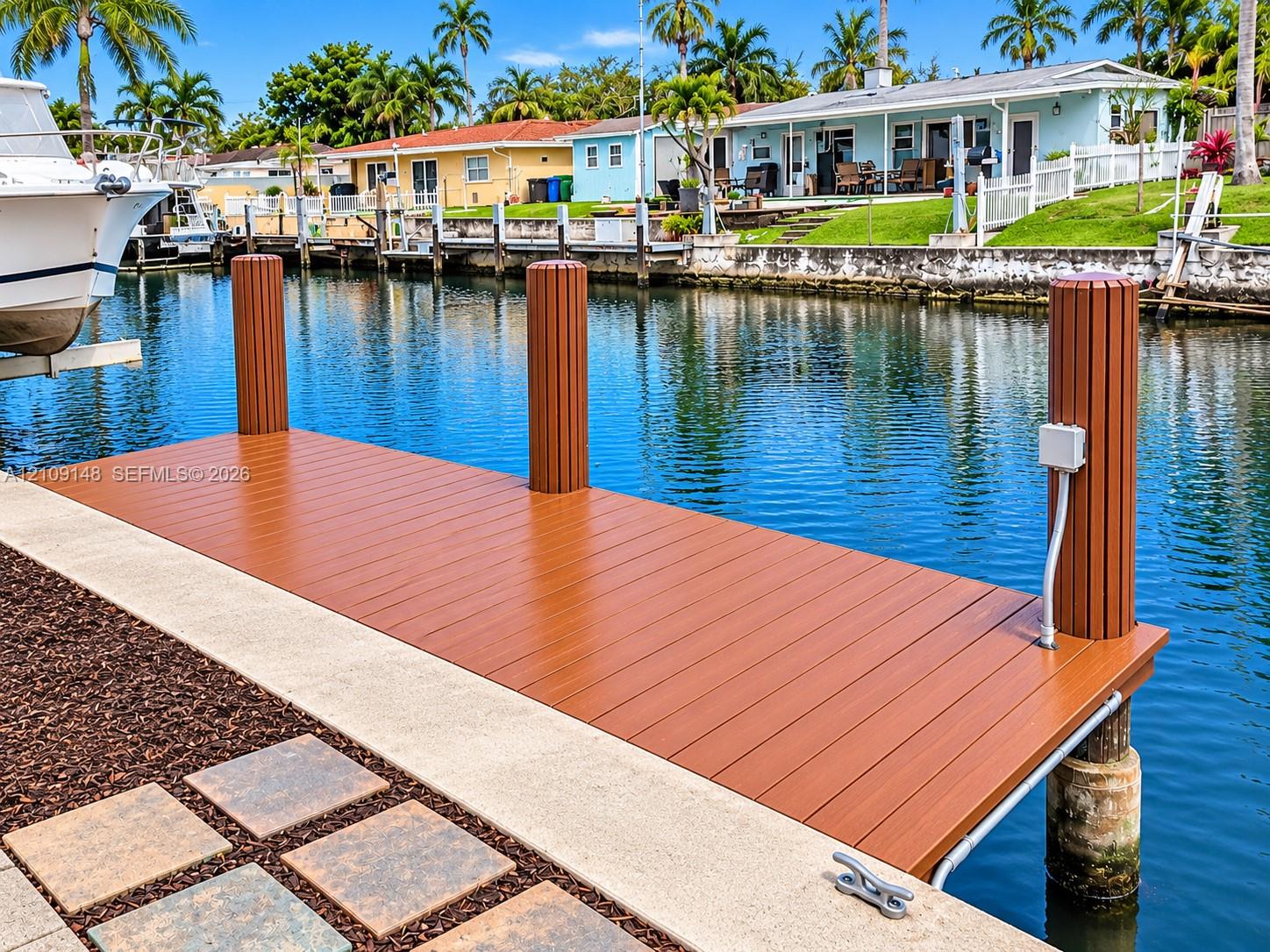Waterfront dock featuring composite decking, vertical pilings, and a concrete bulkhead