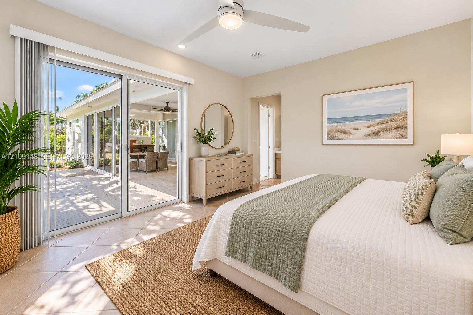 Neutral-toned interior featuring oversized glass sliding doors, tile flooring, and a modern ceiling fan