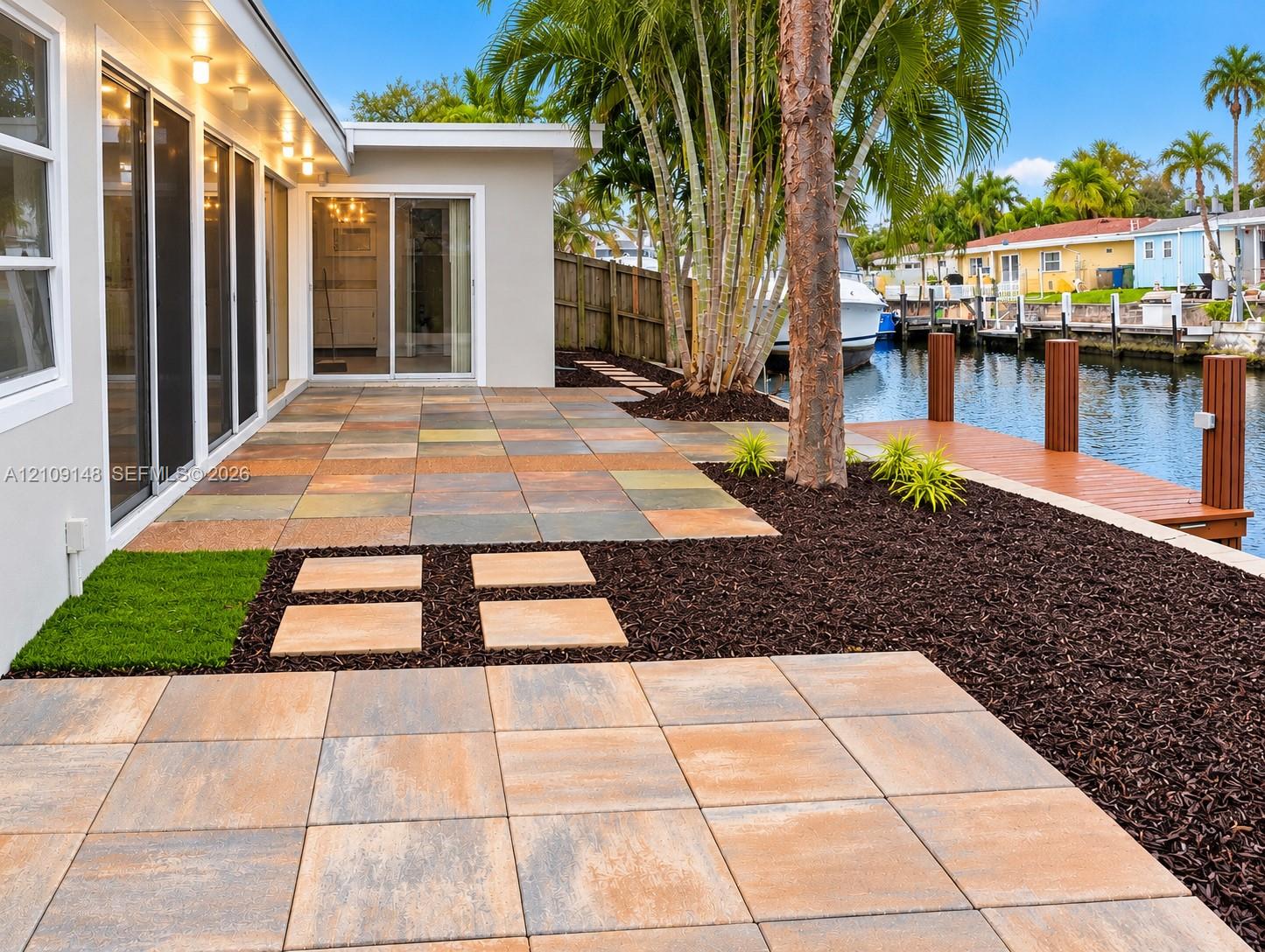 Waterfront patio featuring large-format paver tile flooring, recessed soffit lighting, and a private dock