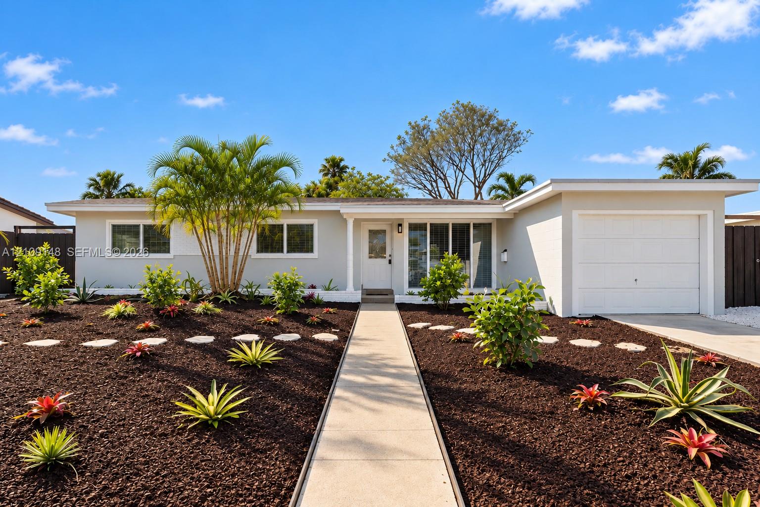 Single-story residence featuring a painted masonry exterior, attached garage, concrete walkway, and landscaped garden with stone path accents Single-story residence featuring a painted masonry exterior, attached garage, concrete walkway, and landscaped garden with stone path accents