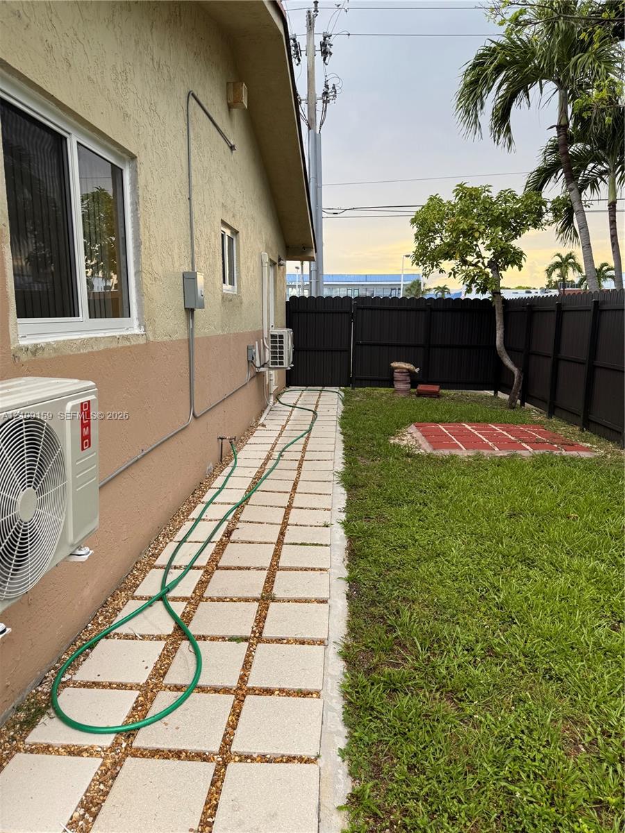 Side yard featuring a paver walkway with gravel inlay, a lawn area, and a privacy fence